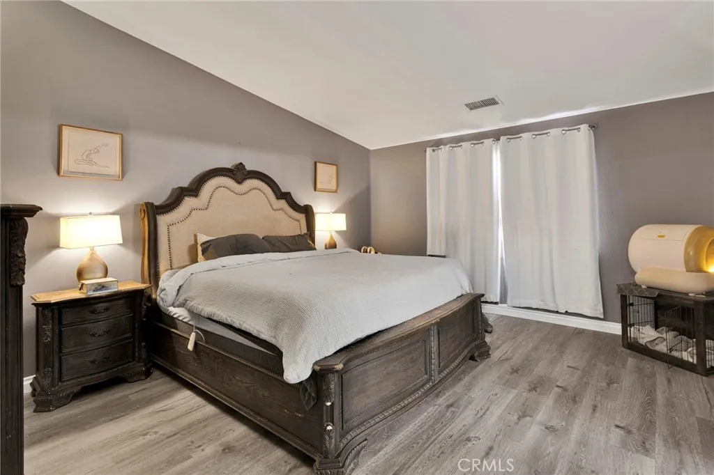 Spaciously designed primary suite accommodates a large bedroom set with continuous modern flooring and a neutral color palette.