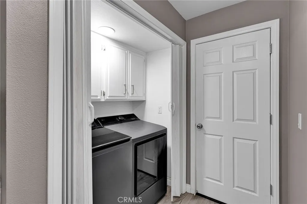 Indoor utility space equipped with modern front-loading laundry machines and clean white overhead storage cabinetry.