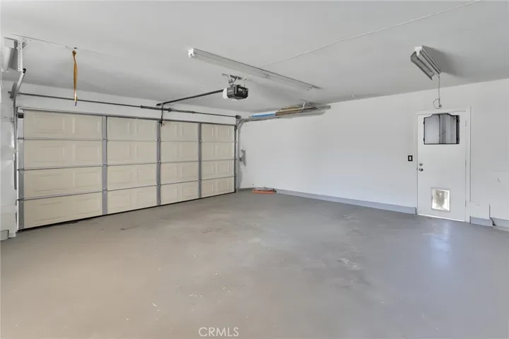 Alternate perspective of the clean garage interior showing the pristine concrete floor and a convenient side-yard pedestrian exit door.
