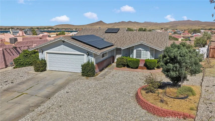 Front aerial perspective highlights the home's striking curb appeal, low-maintenance landscaping, and clean roofline featuring an energy-efficient solar panel system.