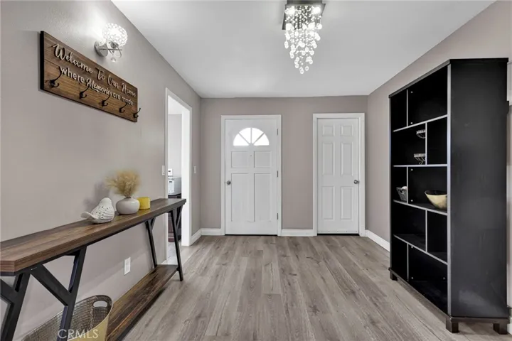Bright front entry hall highlights continuous low-maintenance flooring, updated modern lighting, and direct sightlines into the main living spaces.