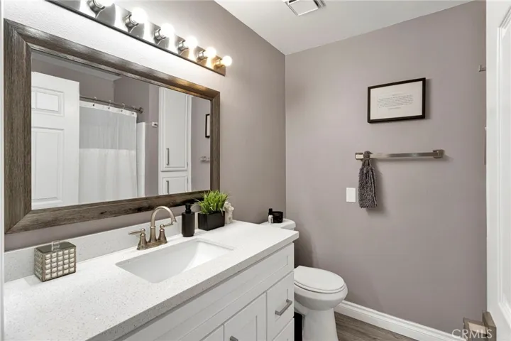Beautifully updated main bathroom features a brilliant white quartz vanity countertop, modern plumbing fixtures, a custom framed mirror, and designer lighting.