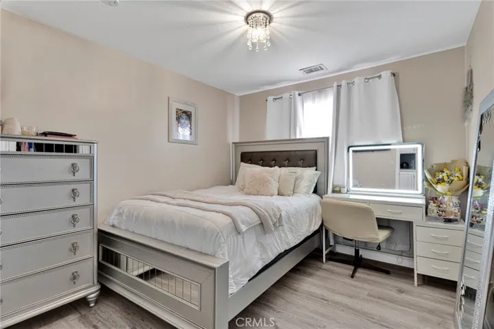 Additional view of the secondary bedroom showcasing the consistent modern flooring, flexible wall space, and bright window placement.