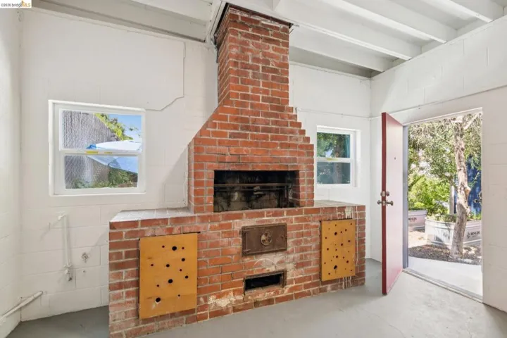 Freestanding red brick fireplace structure featuring an integrated oven and storage compartments
