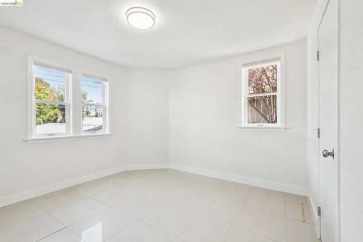 Room featuring white tile flooring, white walls, multiple windows with white trim, and a flush mount ceiling light fixture
