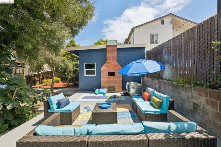 Expansive backyard patio featuring a built-in brick fireplace, concrete paving, and mature trees