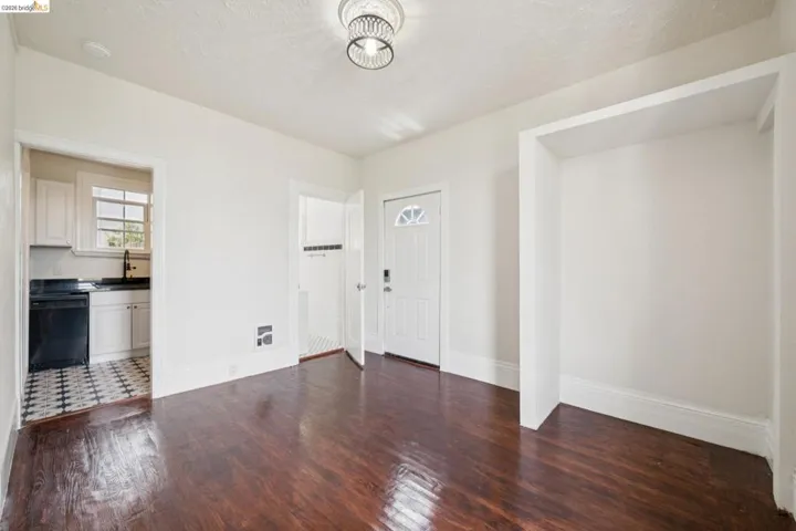 Hardwood-finish flooring extending into the main area, featuring a recessed alcove and a decorative ceiling light fixture