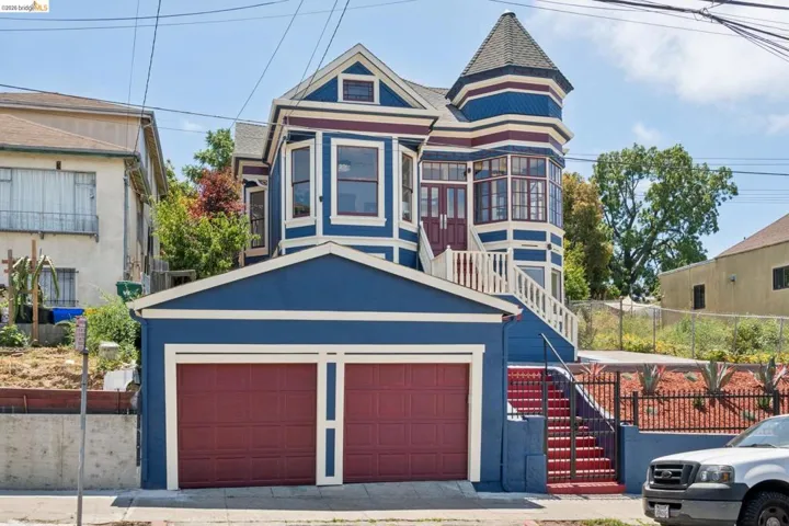 Victorian-style residence with a distinctive turret, prominent gabled roofline, and vibrant blue and maroon exterior trim