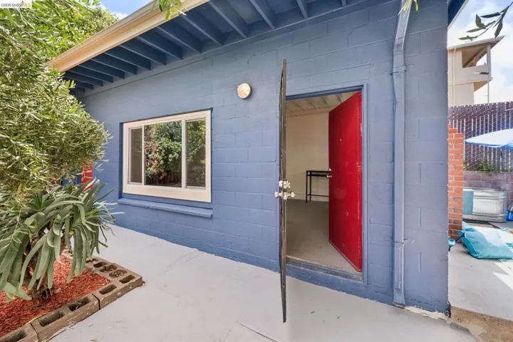 Exterior building with blue block construction, featuring a vibrant red entry door and white-framed window