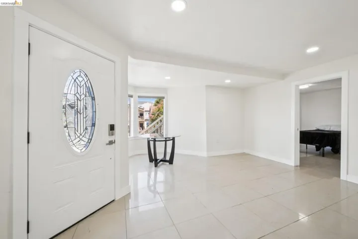 Bright entryway featuring a decorative oval glass insert door with a smart lock