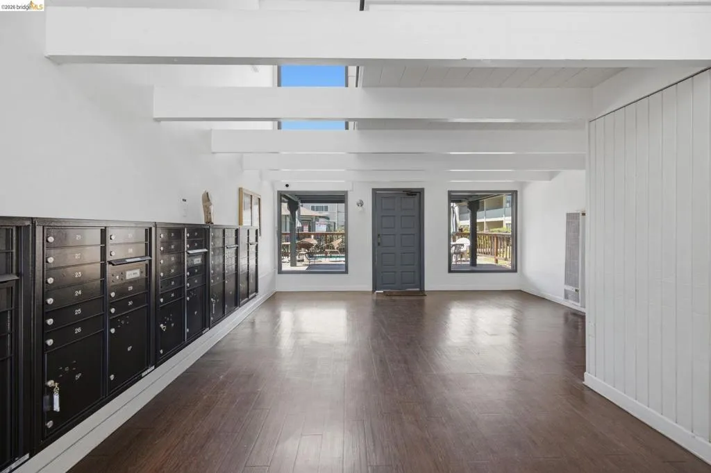 Foyer featuring rich wood-finish flooring, exposed white ceiling beams, and multiple black mailboxes