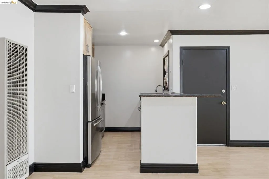 Kitchen area featuring wood-finish flooring, stainless steel refrigerator, and recessed lighting