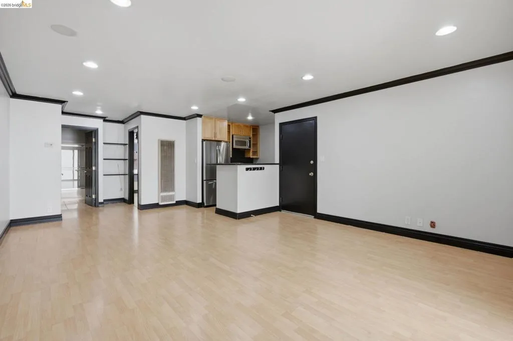 Open-concept living area featuring light wood-finish flooring, recessed lighting, and contrasting dark trim