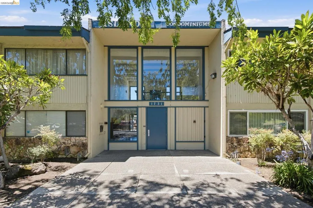 Modern multi-level building facade featuring expansive glazing, stone veneer accents, and a central entryway with a prominent blue door