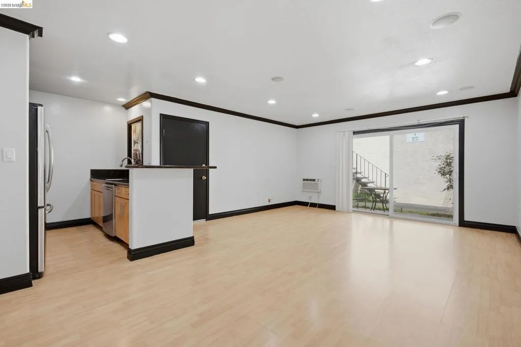 Open-concept living area featuring light wood-finish flooring, recessed lighting, and a built-in kitchen island with a dark countertop