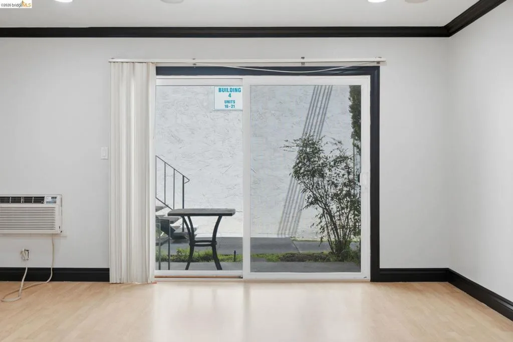 Interior space featuring wood-finish flooring, white walls, and black crown molding and baseboards
