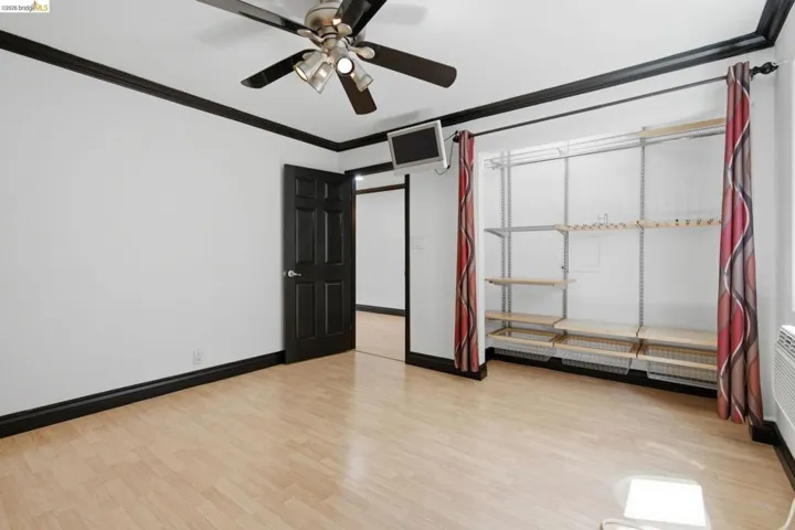 Room featuring light wood-finish flooring, white walls, and contrasting black trim
