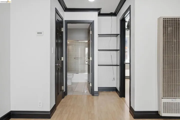Hallway featuring wood-finish flooring, white walls, and dark trim