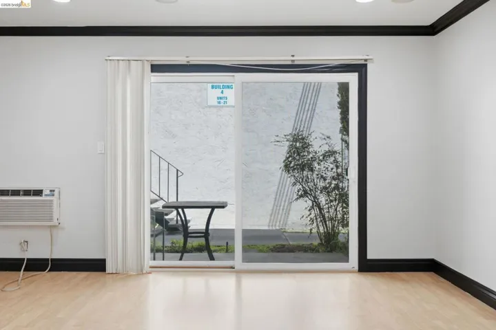 Interior space featuring wood-finish flooring, white walls, and black crown molding and baseboards