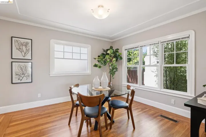 Parquet wood-finish flooring with perimeter border, multiple windows with white trim, crown molding, and a flush mount ceiling fixture