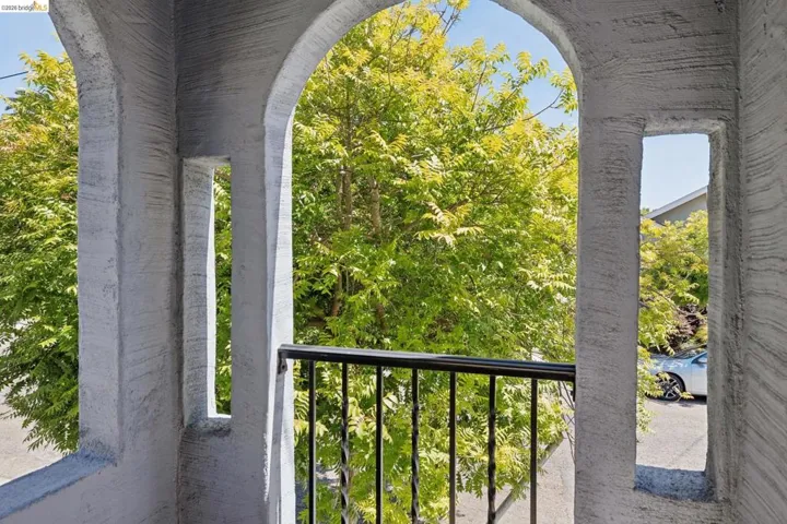 Archway balcony featuring a black wrought iron railing, textured stucco finish, and carved column details