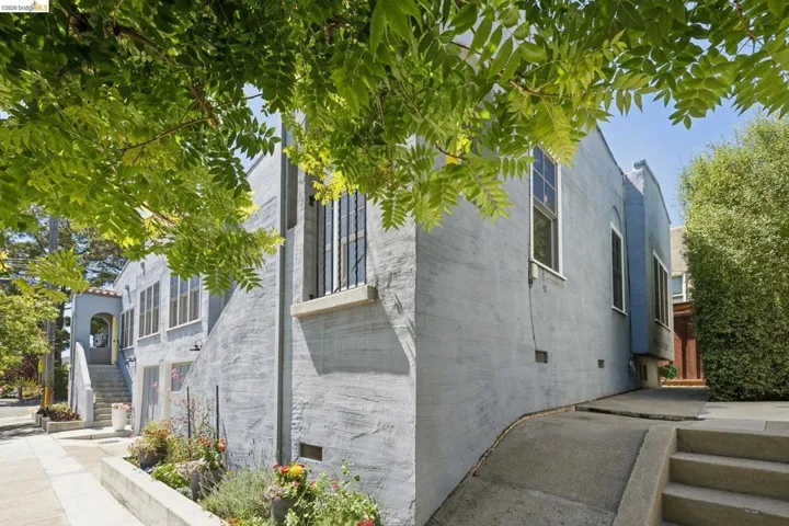Stucco exterior featuring multiple windows, a concrete walkway, and a landscaped planter box