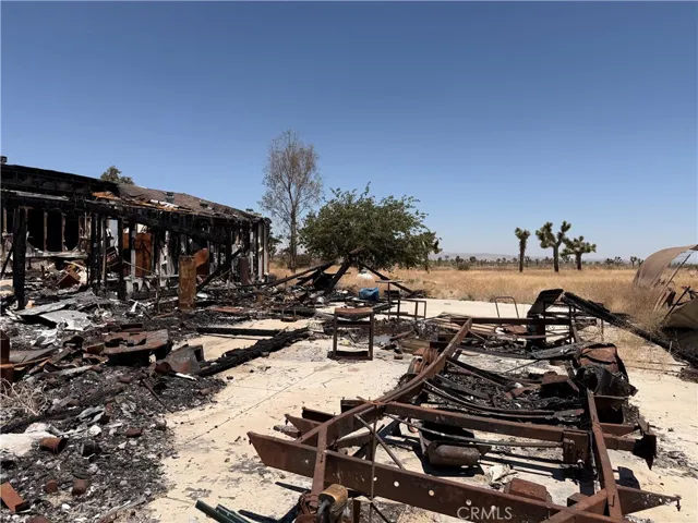 Charred vehicle chassis and backyard debris