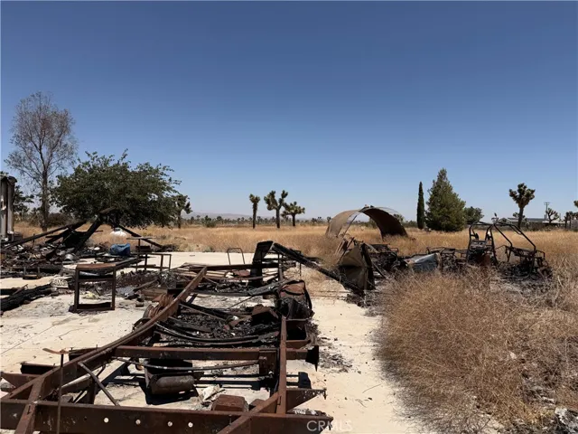 Burned vehicle frame and outbuildings in backyard