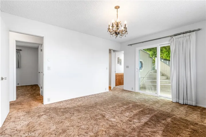 This primary suite offers a comfortable retreat with a sliding glass door that opens to a private deck. The layout provides convenient access to the hallway across from the third room, along with a discreet door that leads down to the lower level. The suite also features its own private en suite bathroom.