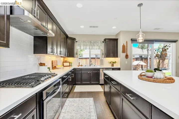 Kitchen featuring rich dark cabinetry, white subway tile backsplash, quartz countertops, new (2026) stainless steel appliances