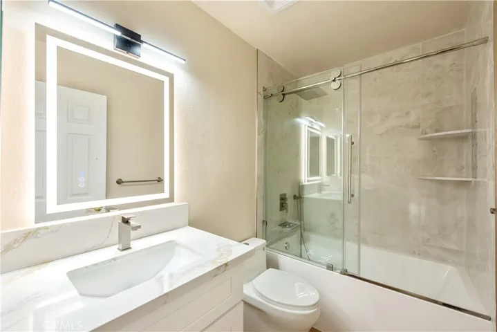 Hallway bathroom- soaking tub, glass doors over tiled enclosure