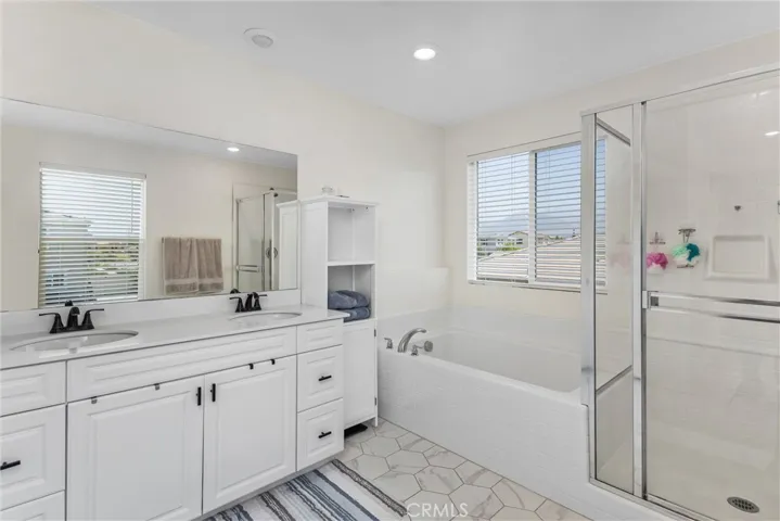 Primary bathroom: tiled flooring, dual vanity sinks, walk in shower and separate tub