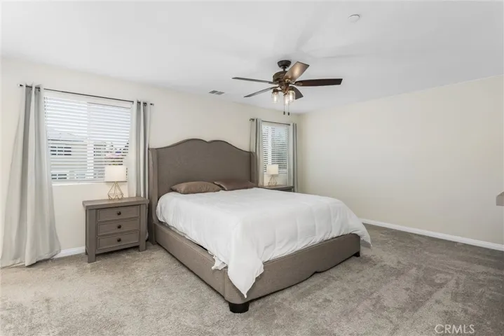 Very spacious primary bedroom with carpet, ceiling fan and walk in closet
