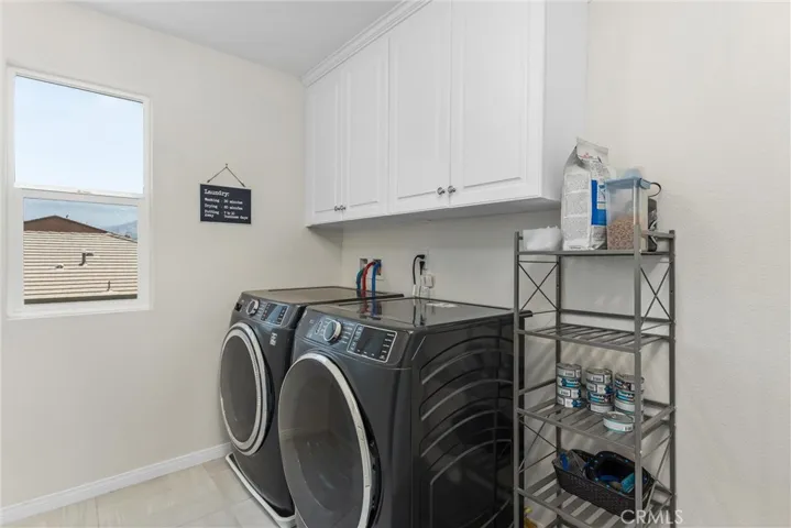 Laundry room upstairs with tiled flooring and cabinets for storage