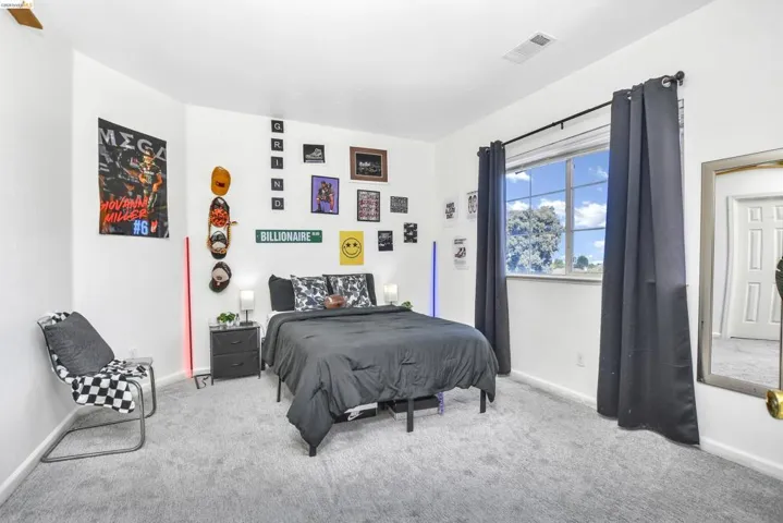 Carpeted room featuring white walls, a large window with a dark curtain rod, and a built-in ceiling vent
