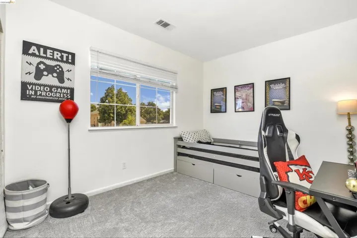 Bright room featuring a large window, neutral wall color, and light gray carpeting