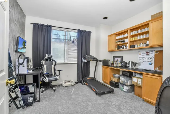 Room featuring carpet flooring, built-in wooden cabinetry with open shelving, and a window with dark curtains
