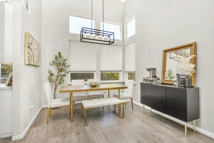 Vaulted ceiling with a linear chandelier, wood-finish flooring, and multiple windows