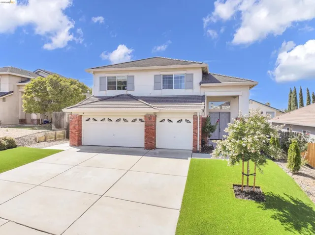 Two-story residence featuring a tile roof, brick accents, and a dual garage