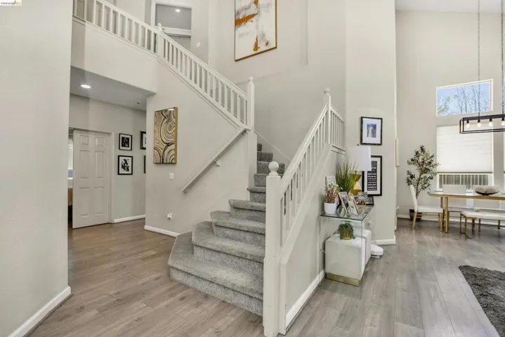 Two-story foyer featuring a grand staircase with white railings and carpeted treads, wood-finish flooring, high ceilings, and recessed lighting