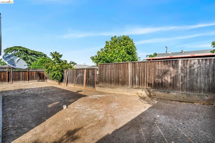 Spacious backyard area featuring wood privacy fencing, ample ground space, and surrounding mature trees