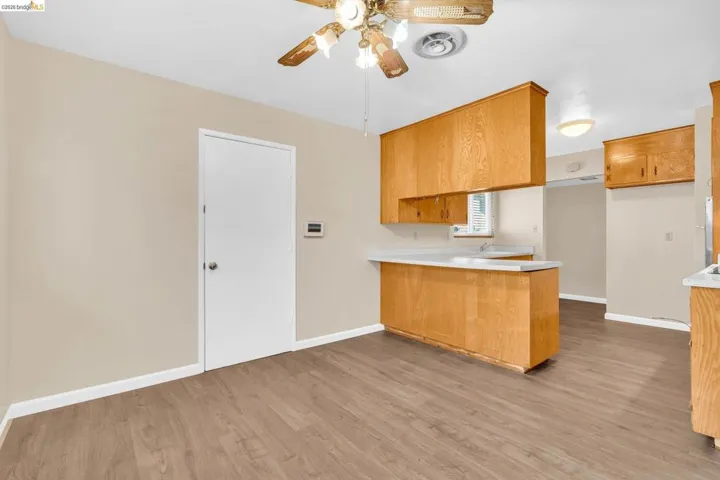 Kitchen area featuring wood-finish flooring and light wood cabinetry with white countertops