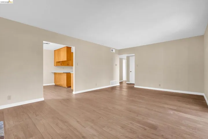 Spacious living area featuring wood-finish flooring, neutral wall tones, and white trim