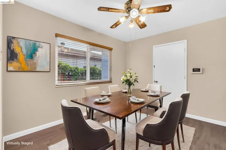 Dining space featuring wood-finish flooring, neutral wall tones, and a window with horizontal blinds