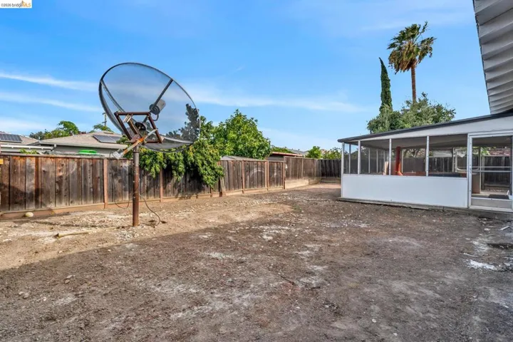 Expansive rear yard featuring a screened-in patio, wood fencing, and mature trees