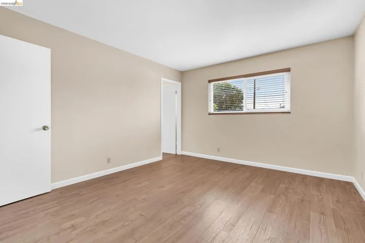 Spacious room featuring wood-finish flooring, neutral-toned walls, and white baseboards