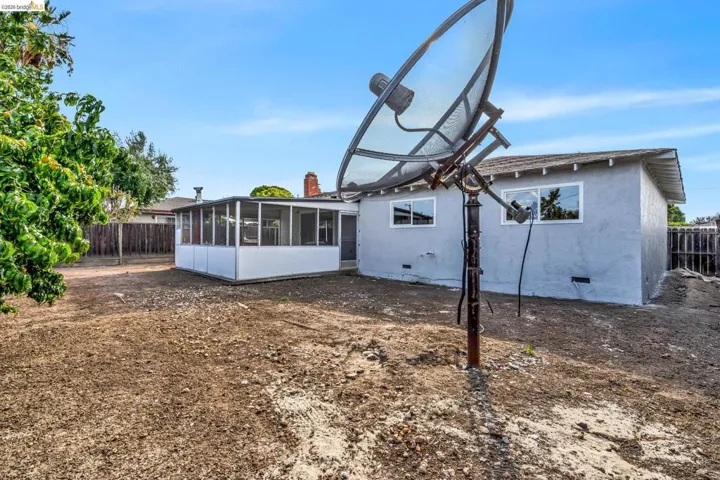 Expansive backyard with a screened porch addition, a stucco exterior, and multiple windows offering natural light