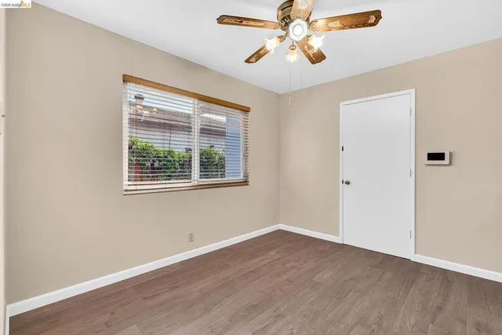 Room featuring wood-finish flooring, a window with horizontal blinds, a ceiling fan with integrated lighting, and neutral wall tones
