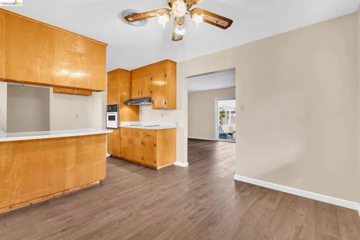 Kitchen area featuring wood-finish flooring, light tone cabinetry, a wall-mounted oven, and a built-in range hood