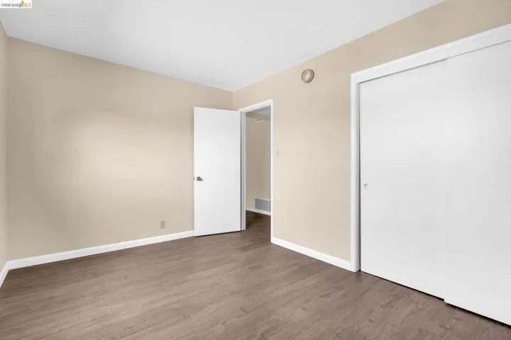 Neutral-toned room featuring wood-finish flooring, white baseboards, and a white ceiling